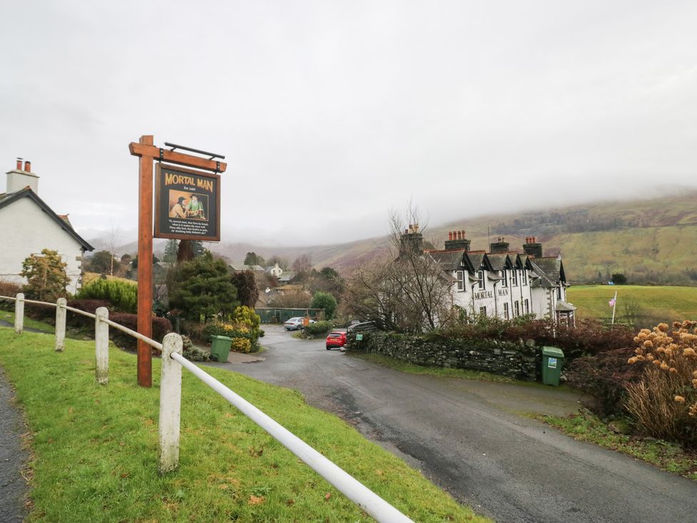 A sign for Mortal Man with buildings and a road in Troutbeck