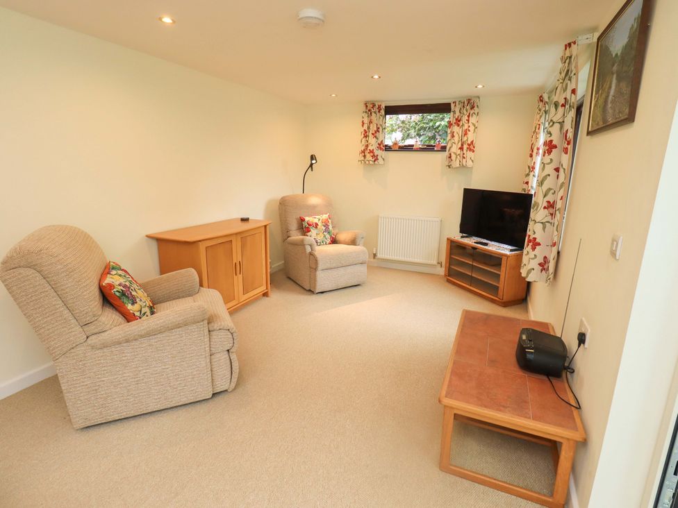 A living room with two recliners and a TV stand at Rowanberry Cottage in Grasmere