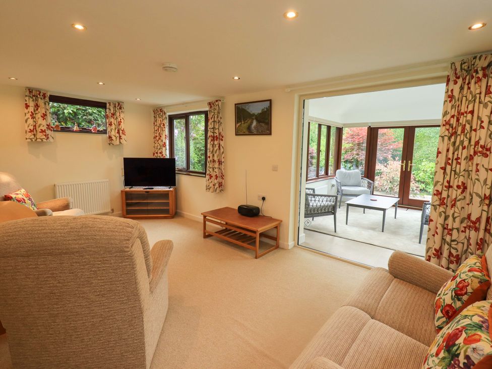 A living room with a sofa, armchair, and television at Rowanberry Cottage in Grasmere