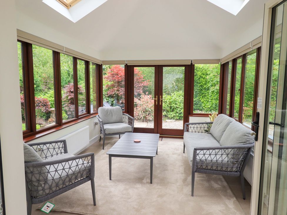 A conservatory with seating and a table at Rowanberry Cottage in Grasmere