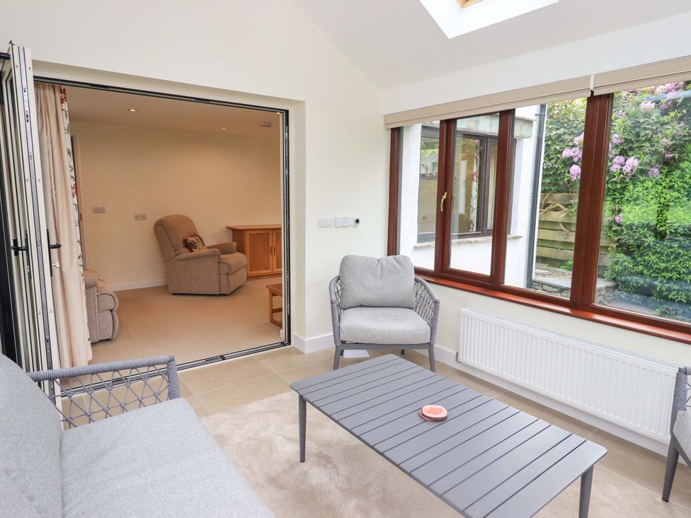 A conservatory with seating and a coffee table at Rowanberry Cottage in Grasmere