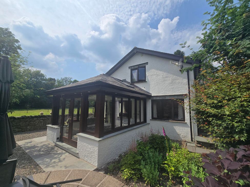 A house with a conservatory and garden at Rowanberry Cottage in Grasmere