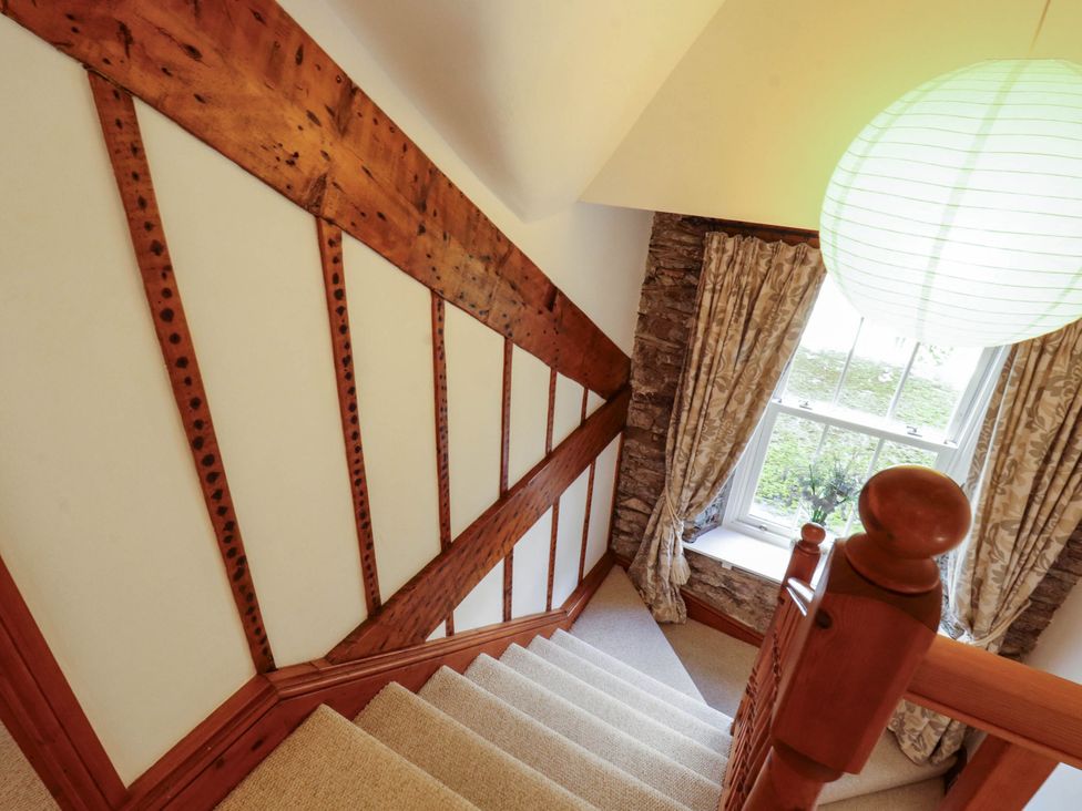 A staircase with wooden railing and window at High Raise in Grasmere