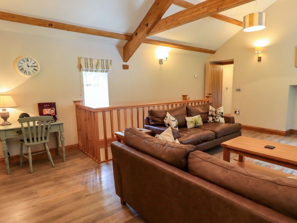 A living room with a sofa and a table lamp at Abbots Reading Cottage Lakeside