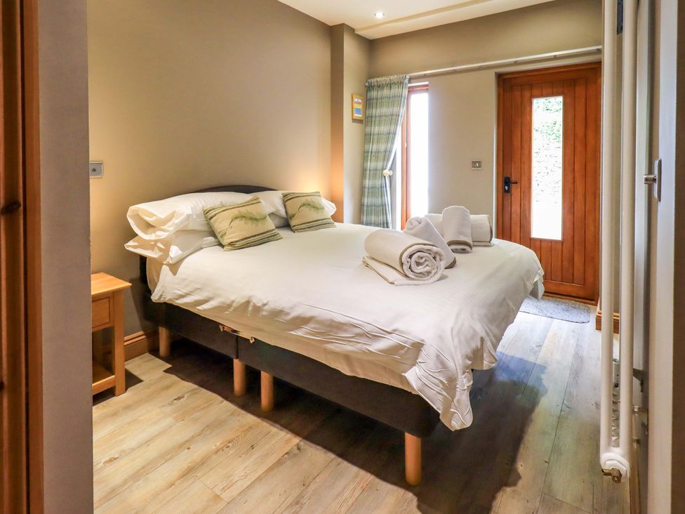 A bedroom with a bed and nightstand at Abbots Reading Cottage Lakeside