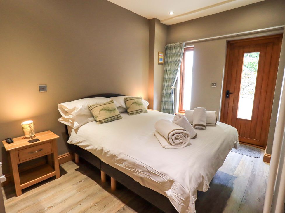 A bedroom with a bed towels and a door at Abbots Reading Cottage Lakeside