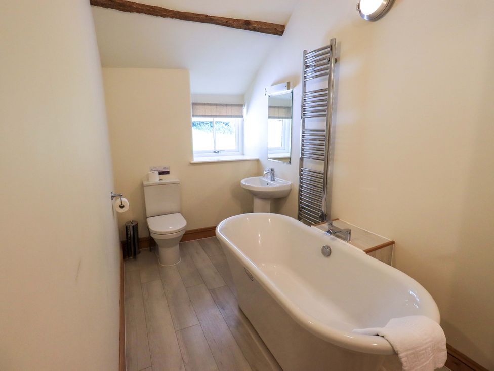 A bathroom with a bathtub, toilet, sink, and towel rail at Abbots Reading Cottage Lakeside