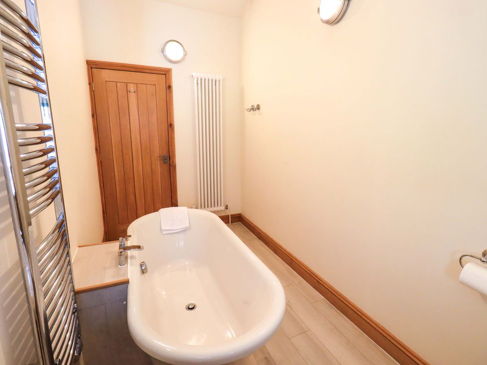 A bathroom with a bathtub and radiator at Abbots Reading Cottage in Lakeside