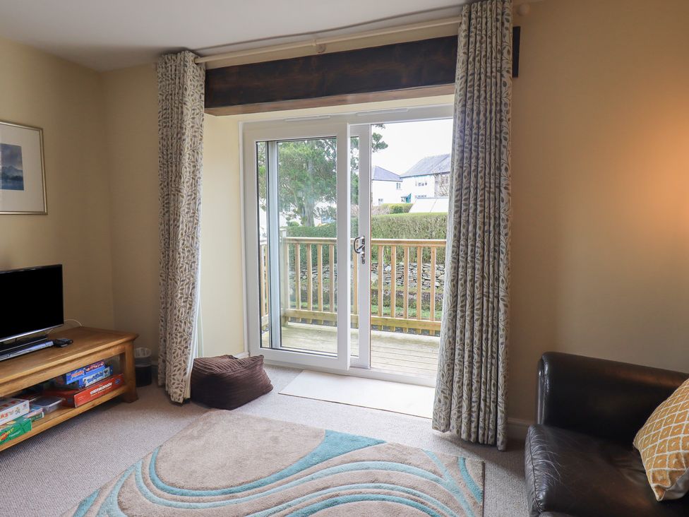 A living room with a television, coffee table, and sliding door at A River Runs By in Staveley