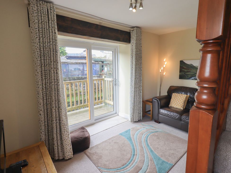 A living room with a sofa and a window leading to a balcony at A River Runs By in Staveley