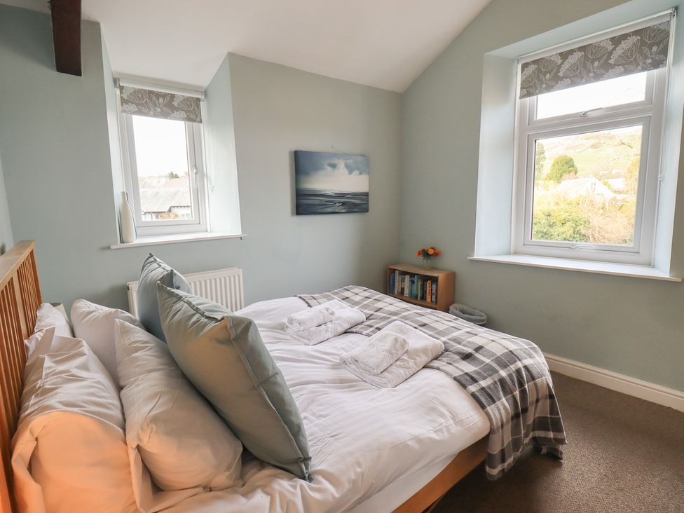 A bedroom with a bed and windows at A River Runs By in Staveley