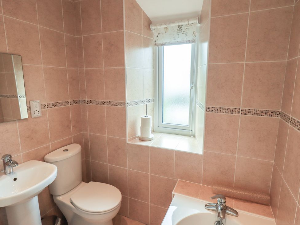 A bathroom with a sink, toilet, and window at A River Runs By Staveley