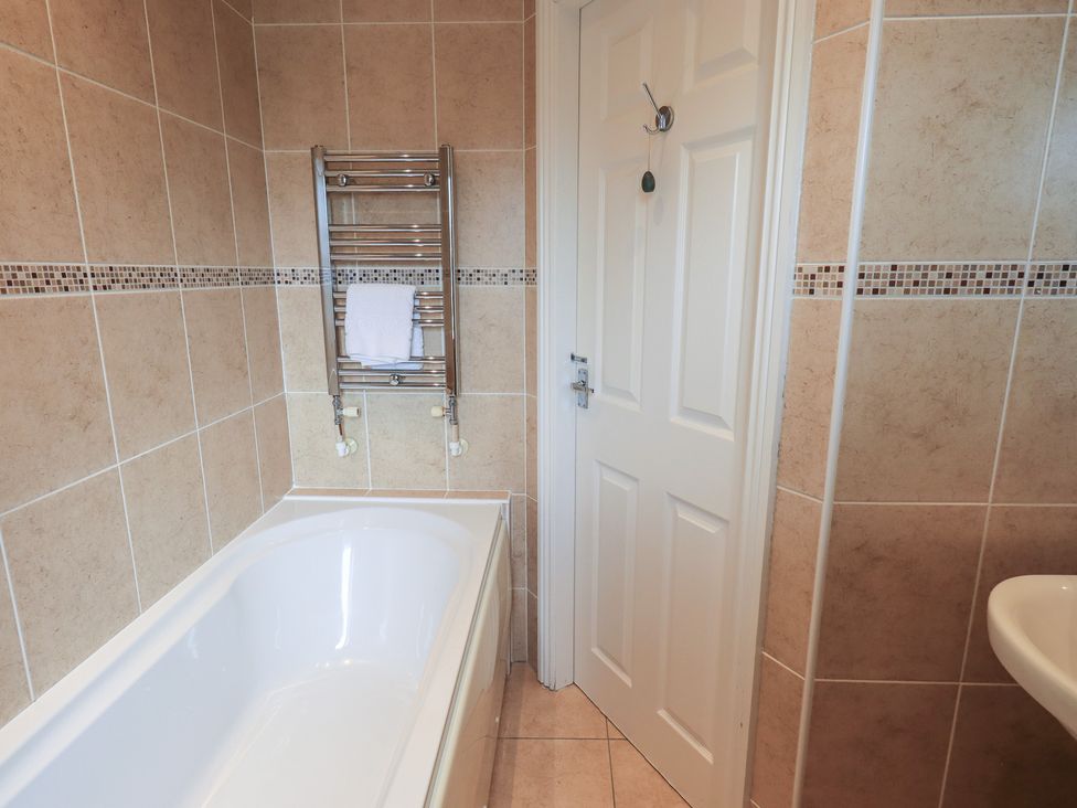 A bathroom with a bathtub and towel rail at A River Runs By Staveley