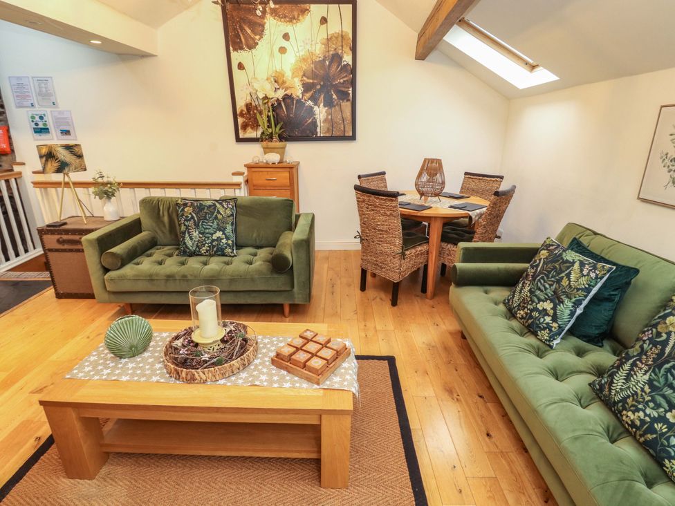 A living room with sofas and a dining area at Workshop Cottage in Bowness