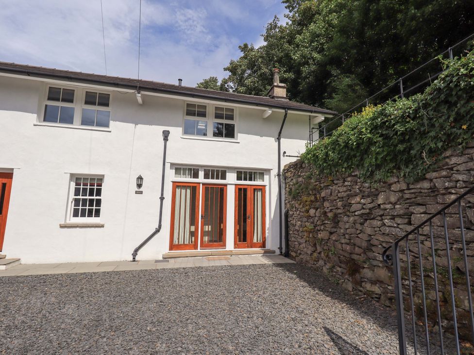 An exterior view of a building with a stone wall and wooden doors at Abbots Reading Suite in Lakeside