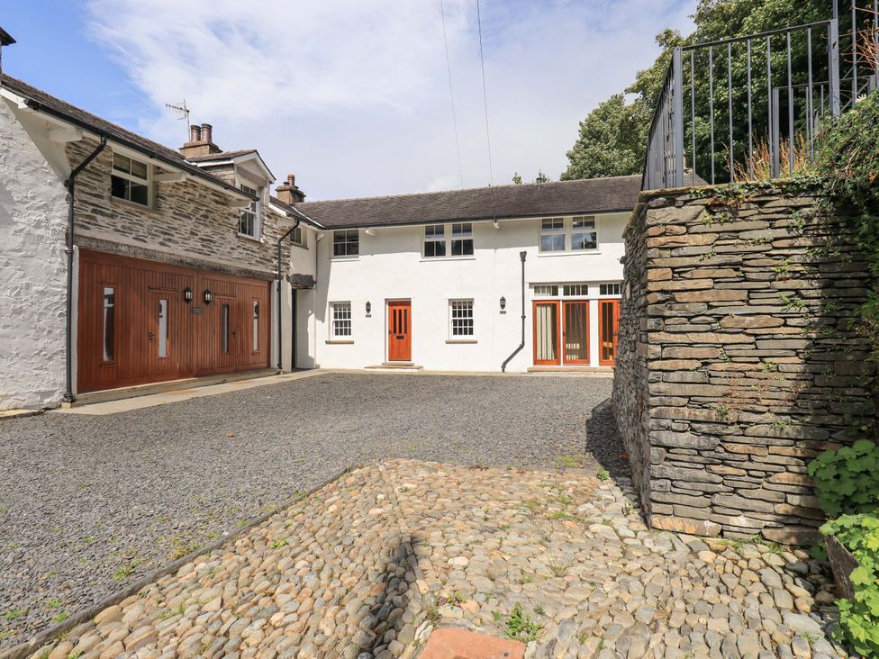 An outdoor view of a house with a garage and stone wall at Abbots Reading Suite, Lakeside
