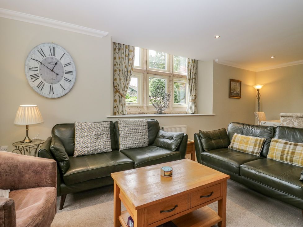 A living room with sofas, a table, and a clock at Middlerigg in Troutbeck