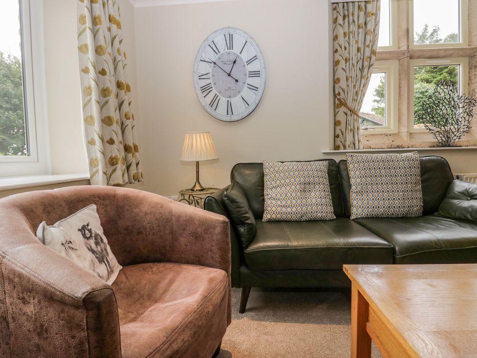 A living room with a clock, sofa, armchair, and lamp at Middlerigg in Troutbeck