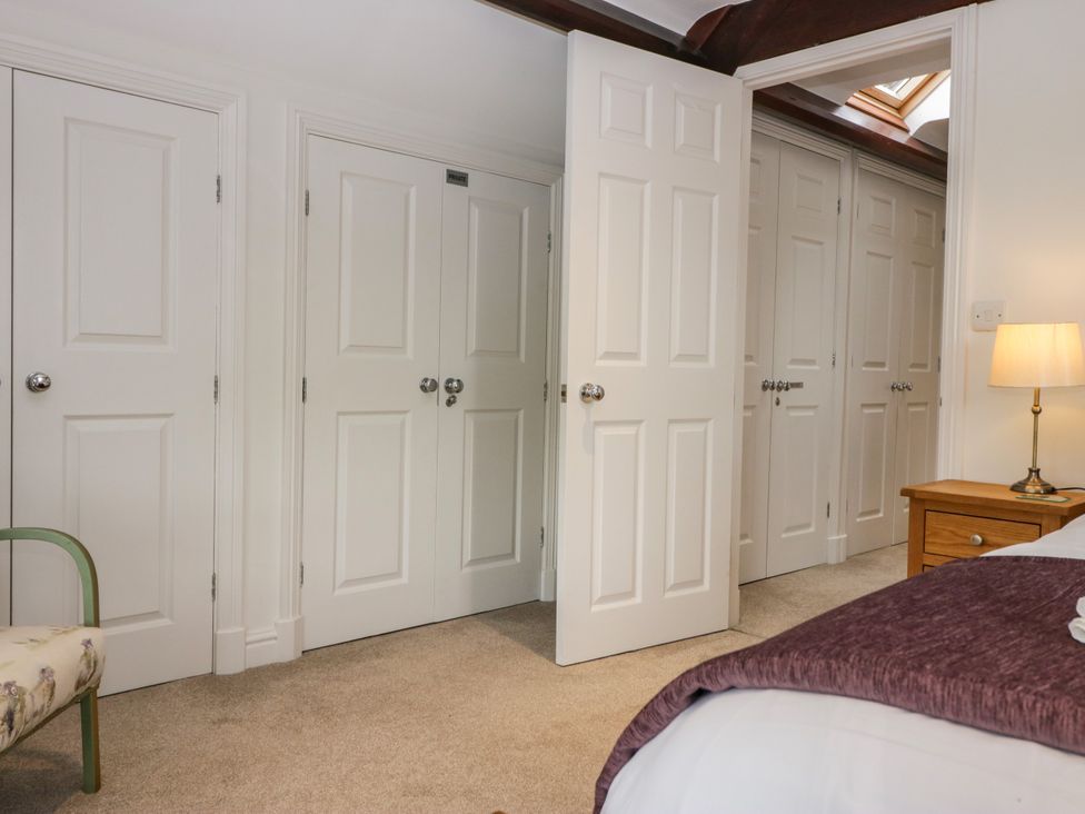 A bedroom with doors, a lamp, and a nightstand at Middlerigg in Troutbeck
