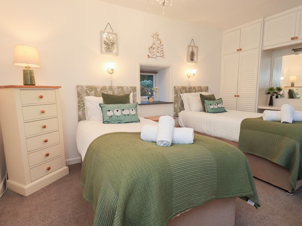 A bedroom with two beds and a lamp at Fairfield Cottage in Grasmere