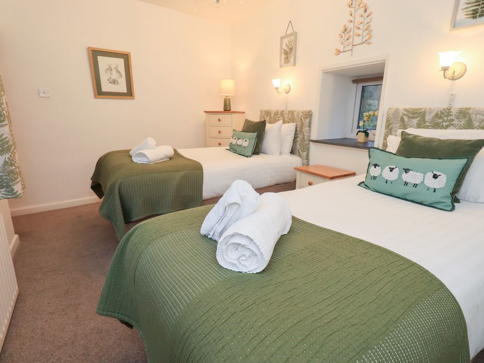 A bedroom with two beds and decorative pillows at Fairfield Cottage in Grasmere