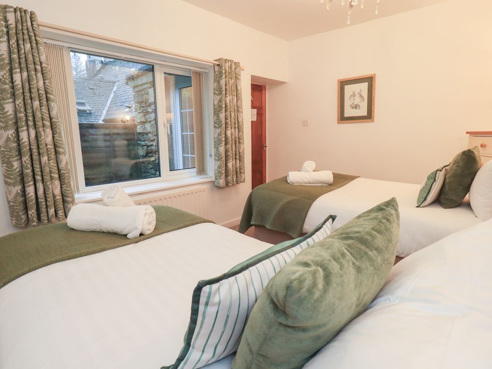 A bedroom with two beds and a window at Fairfield Cottage in Grasmere