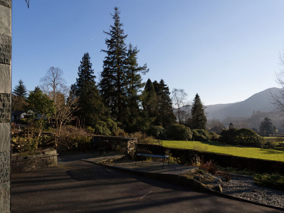 A garden with trees and mountains at Fairfield Cottage in Grasmere