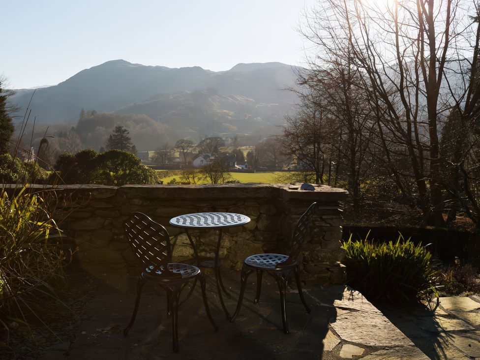 A patio with a table and chairs overlooking mountains at Fairfield Cottage in Grasmere