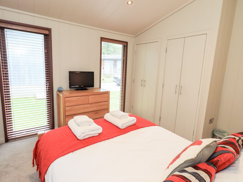 A bedroom with a bed, dresser, and television at Thie Loghey in Hawkshead