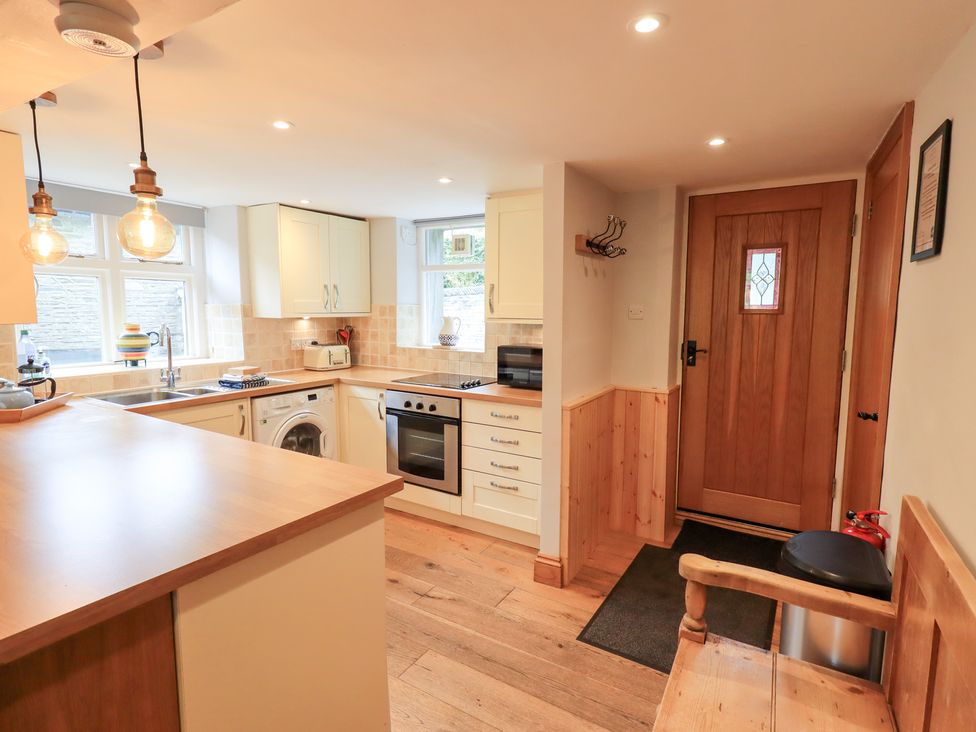 A kitchen with appliances and a door at Boxwood Cottage in Troutbeck