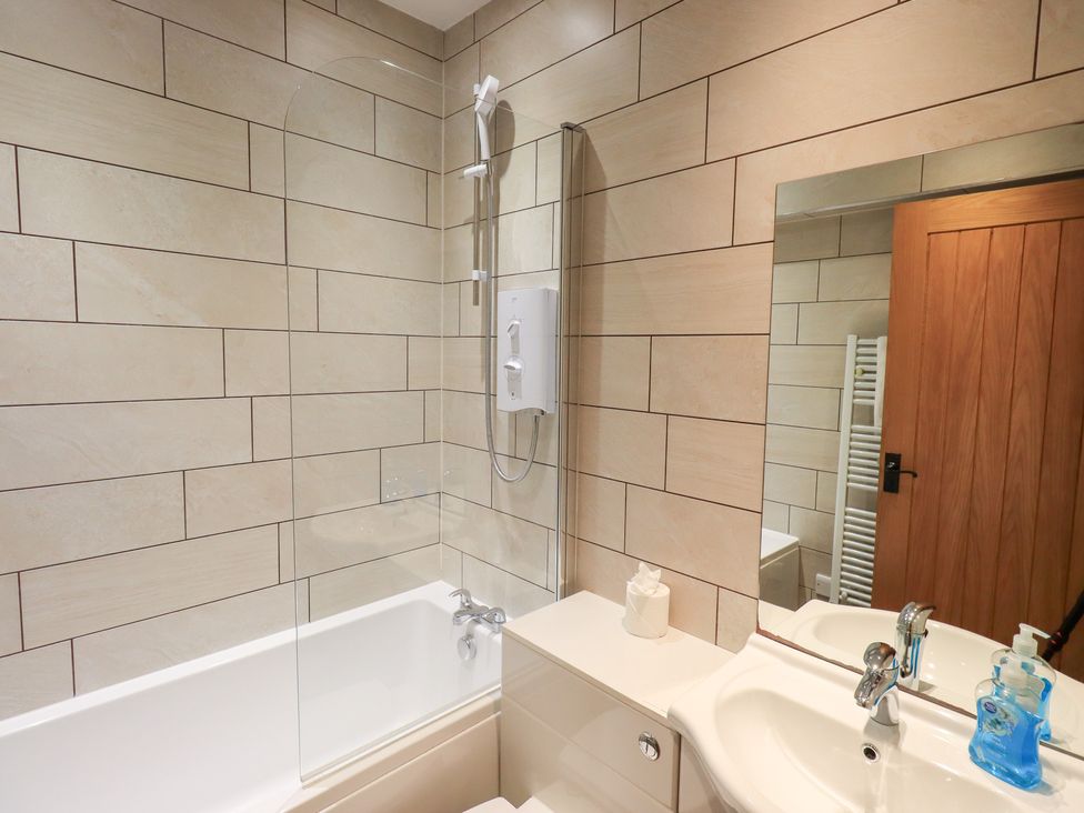 A bathroom with a shower, bathtub, and sink at Boxwood Cottage in Troutbeck