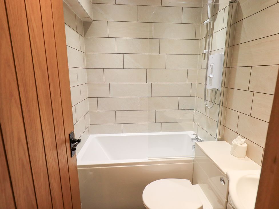 A bathroom with a bathtub and toilet at Boxwood Cottage in Troutbeck