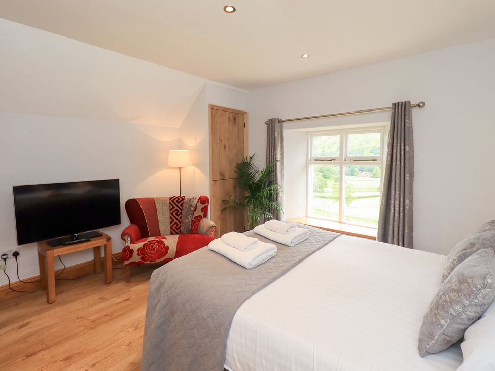 A bedroom with a bed and television at Boxwood Cottage in Troutbeck
