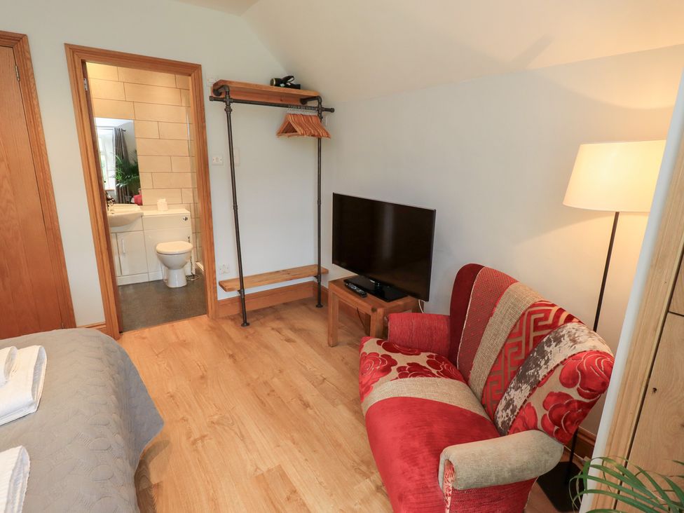 A bedroom with a television and armchair at Boxwood Cottage in Troutbeck