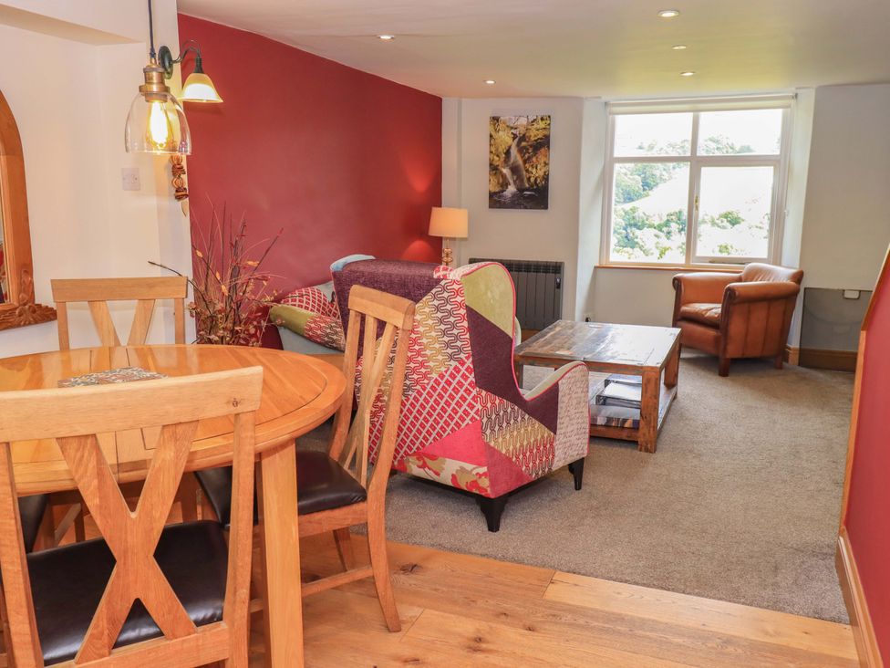 A living room with a dining table and chairs along with a sofa and armchair at Boxwood Cottage in Troutbeck