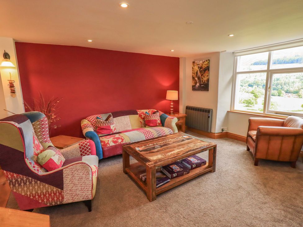 A living room with a sofa, coffee table, and lamp at Boxwood Cottage in Troutbeck