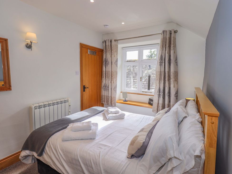 A bedroom with a bed, window, and mirror at Boxwood Cottage in Troutbeck