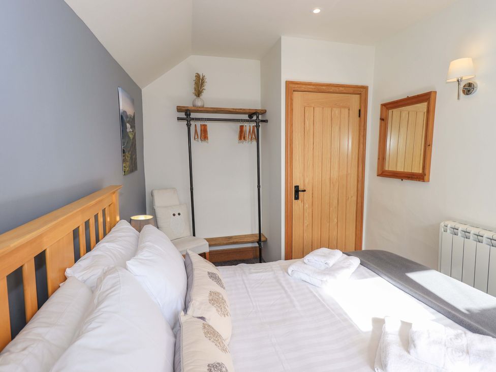 A bedroom with a bed and shelving at Boxwood Cottage in Troutbeck