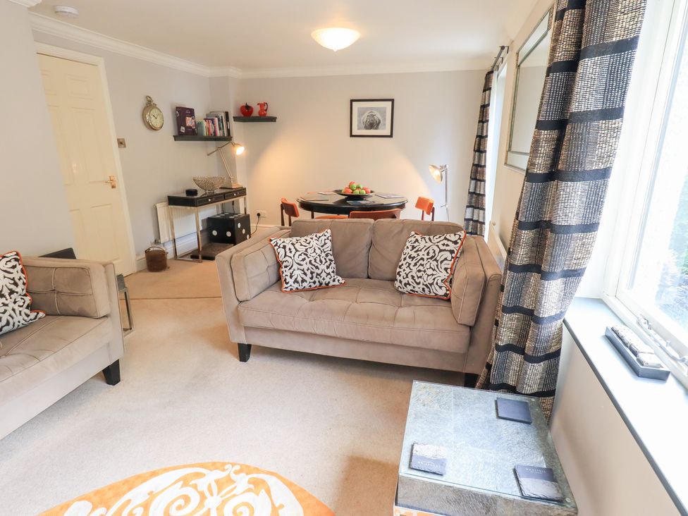 A living room with sofas, a dining table, and shelves at Ghyll Heights in Ambleside