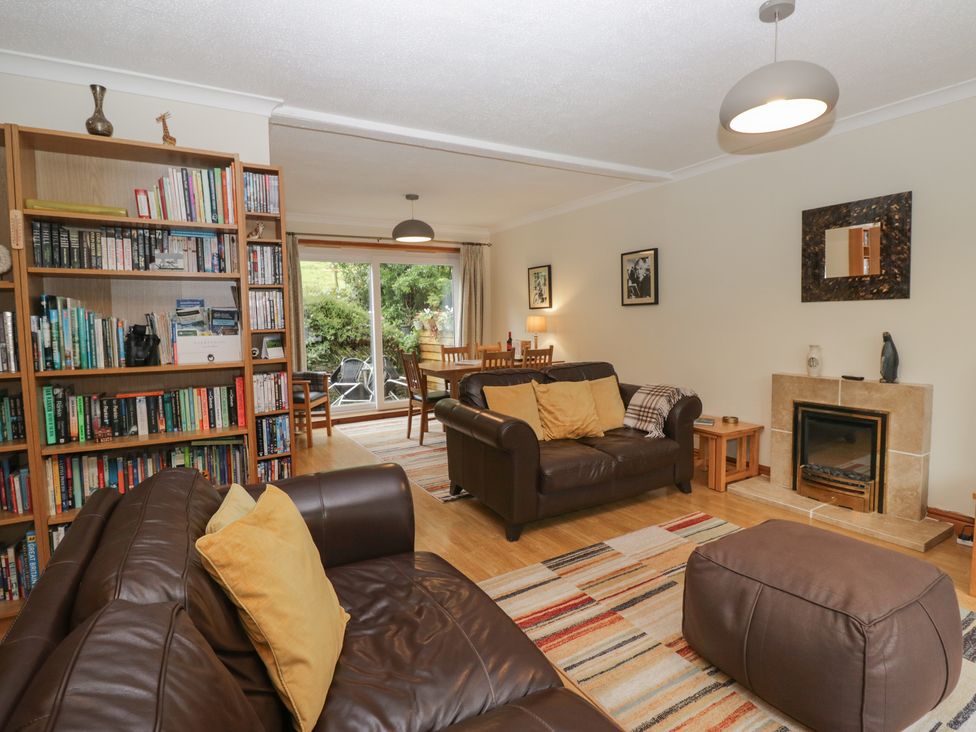 A living room with a bookshelf, sofa, and dining area at Redwood in Ambleside