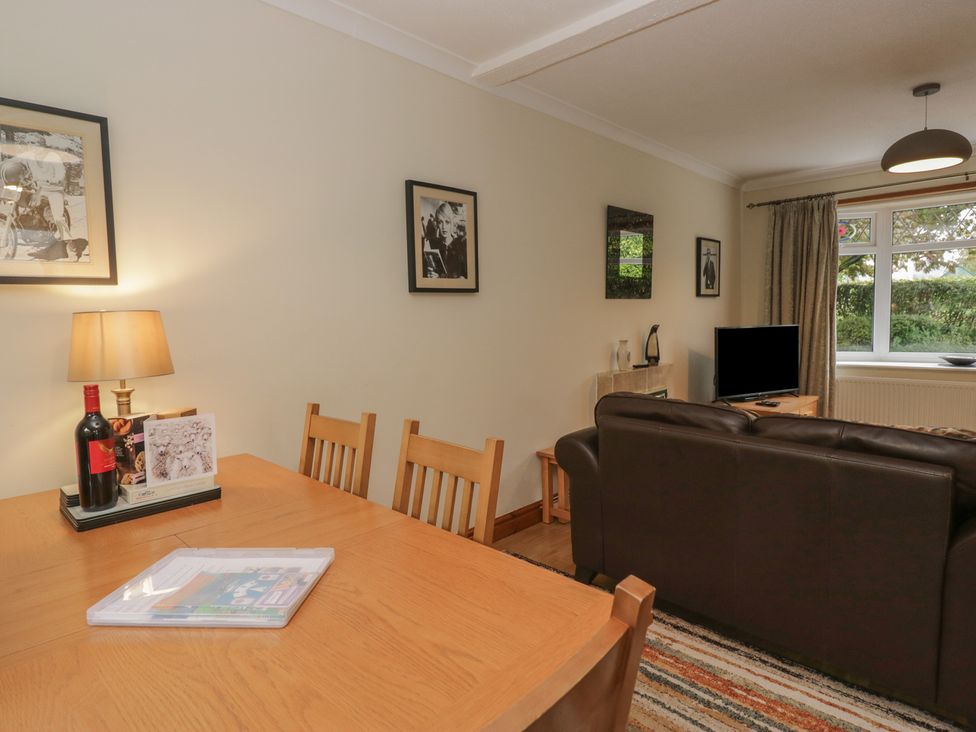 A living room with a table, chairs, and a television at Redwood in Ambleside
