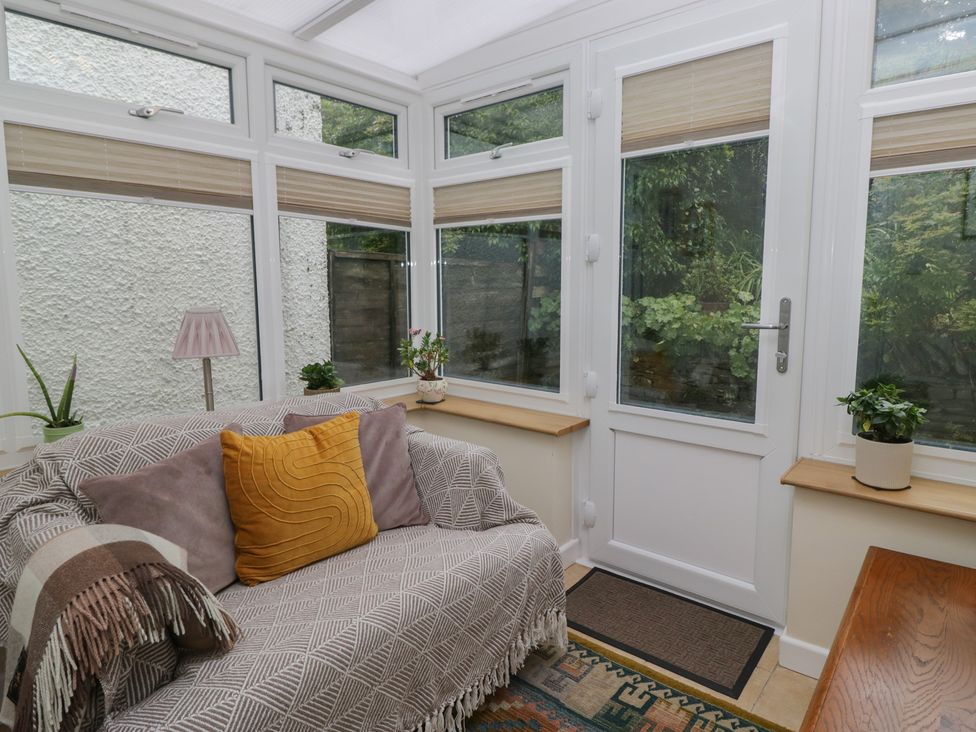 A conservatory with a sofa and plants at Redwood in Ambleside