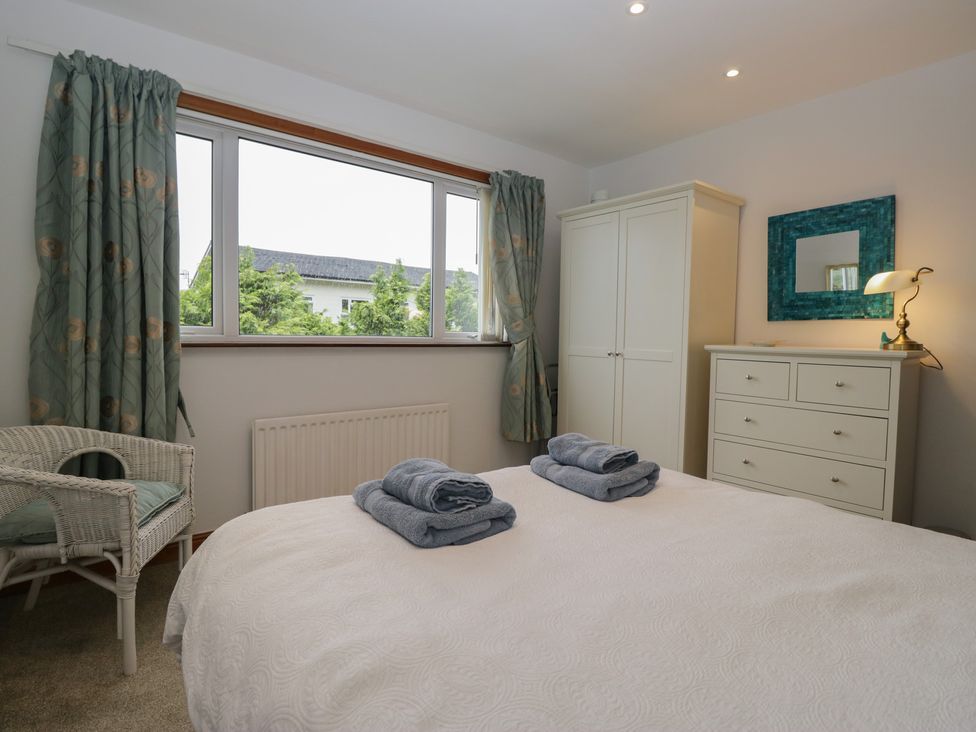 A bedroom with a bed, wardrobe, dresser, and window at Redwood in Ambleside