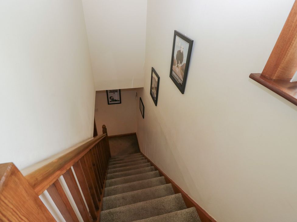A staircase with a wooden handrail and pictures on the wall at Redwood in Ambleside