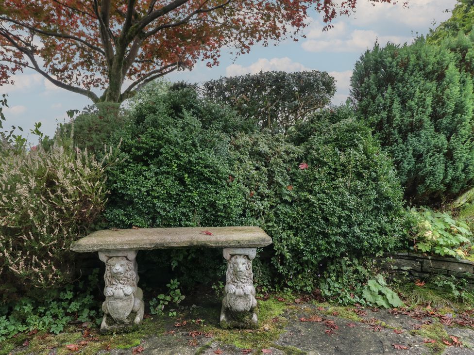 A garden with a stone bench surrounded by bushes at Redwood in Ambleside