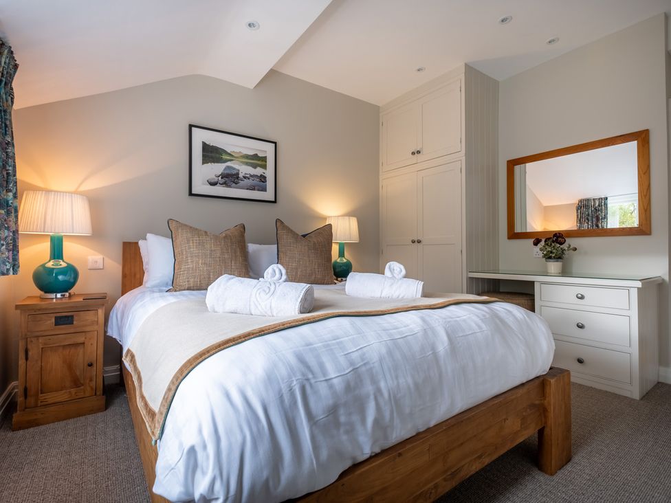 A bedroom with a bed, nightstand, lamp, mirror, and desk at Goody Raise in Grasmere