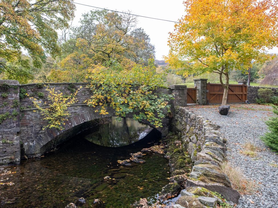 A bridge over a stream with a gate and trees at Goody Raise in Grasmere