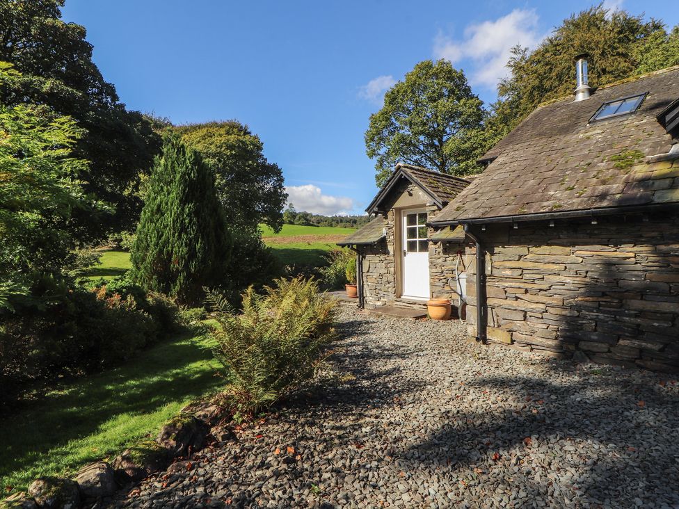An outdoor view of a cottage with a stone wall and gravel path at Hawkshead Hall in Hawkshead