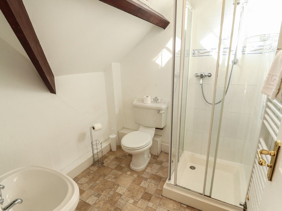 A bathroom with a shower, toilet, sink, and bidet at Hawkshead Hall in Hawkshead