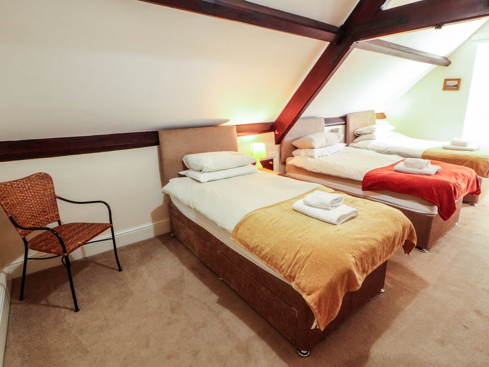 A bedroom with three beds and a chair at Hawkshead Hall in Hawkshead
